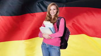female student from Germany standing in front of German flag smiling