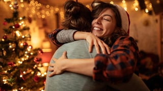 mom with christmas hat on hugging daughter